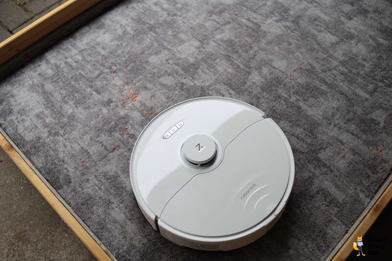 Roborock S8 Pro Ultra reinigt Linsen beim Saugtest auf einem Teppichboden.